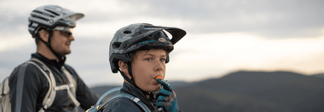 Radfahrer, der unterwegs aus einem Trinkrucksack trinkt